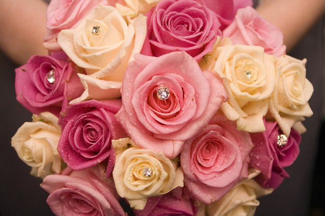 Detail of a bouquet of pink and peach colored roses. Several roses have shimmering diamonds nestled in their centers.