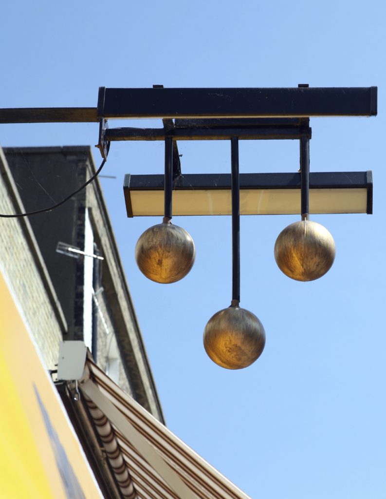 The famous three gold balls sign of a pawnbroker's shop, above a street in Great Yarmouth, Norfolk, eastern England.